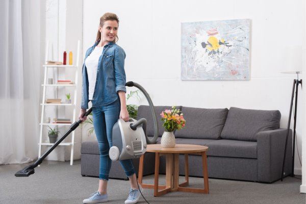 smiling-woman-with-vacuum-cleaner-in-hands-looking-away-picture-id926608964