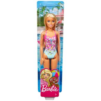 une Barbie poupée séance sur le plage avec une rose parapluie