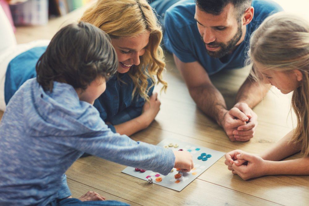 A família está jogando um jogo de tabuleiro duas pessoas passam o